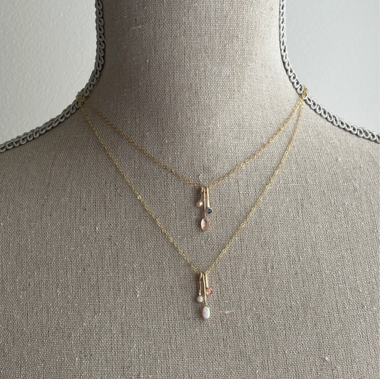 gemstone drop necklaces in gold on a textured bust