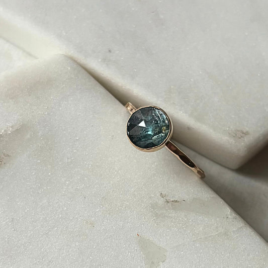 A kyanite stacking ring with a blue gemstone, set in a gold-filled or sterling silver band, displayed on a marble surface.