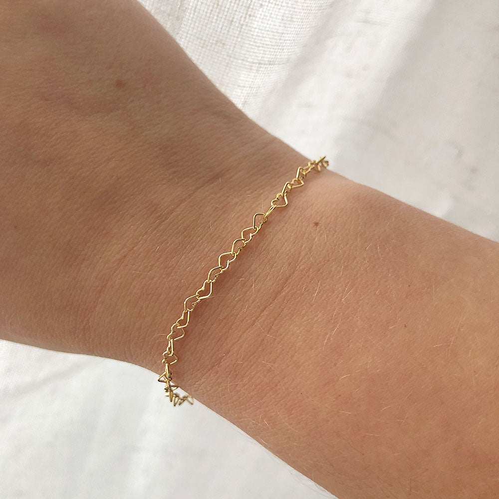 woman's wrist featuring a dainty gold heart bracelet