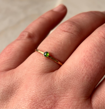 A petite emerald gemstone ring on a finger