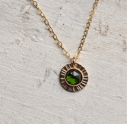 An emerald gemstone pendant on a neutral background.