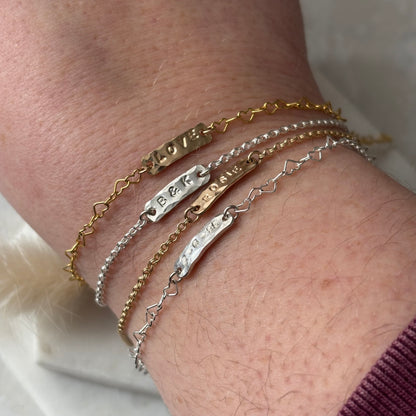 Close-up of a wrist wearing multiple gold and silver bracelets with engraved designs.