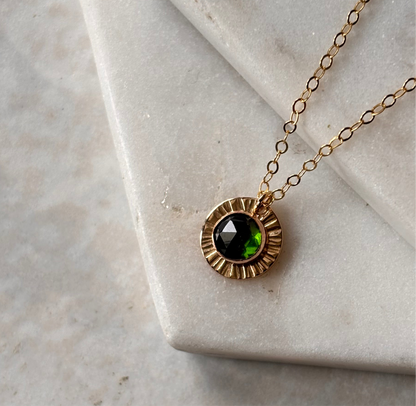 a rose cut emerald gemstone necklace on a marble background with dainty chain