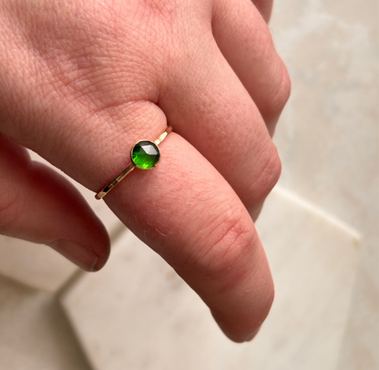 A rose-cut lab-grown emerald ring set in a 14k gold-fill band, displayed on a finger.