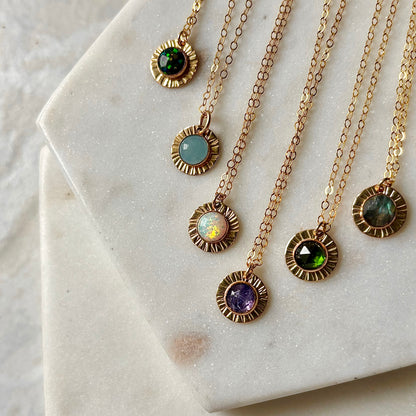 Set of gold necklaces with gemstone pendants on a marble surface