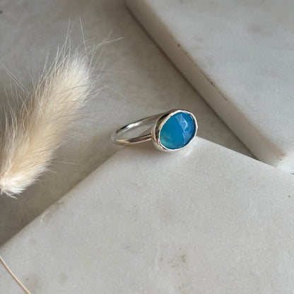 Silver ring with a blue stone on a light surface with dried grass.