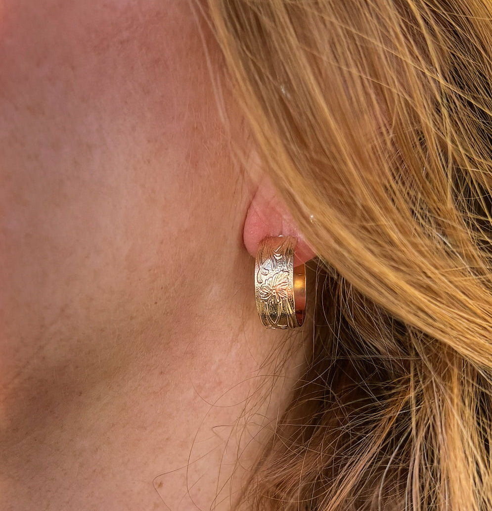 Gold hoop earring worn by a person with blonde hair.