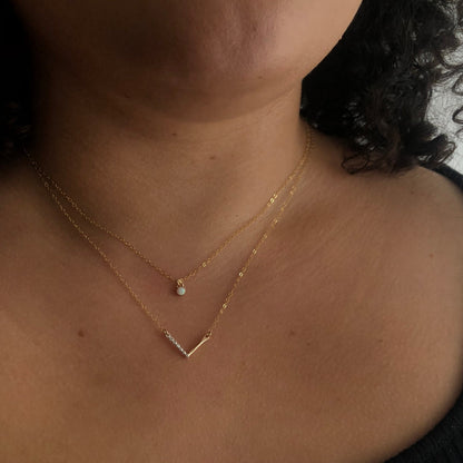 A person wearing a chevron necklace with a combination of silver and gold-fill metals.