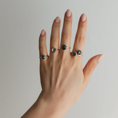 A woman's hand displaying five kyanite rings in gold.