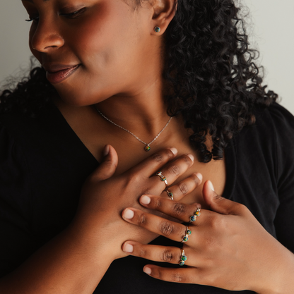 A person wearing a pair of black opal stud earrings and rings