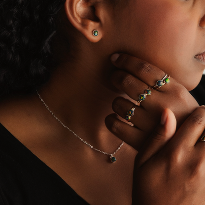 A person wearing black opal necklaces and rings.