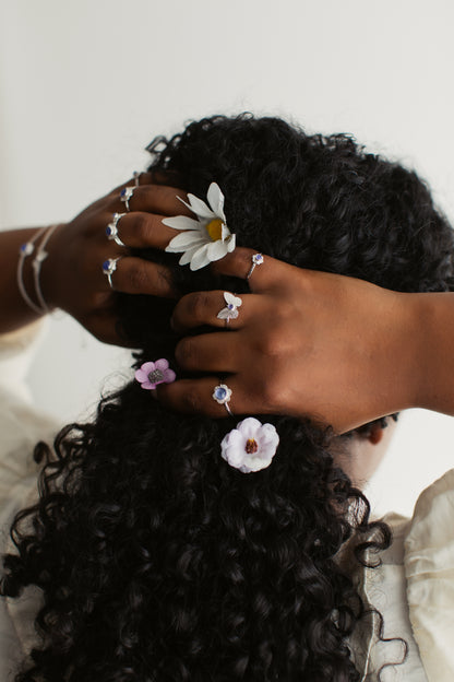 A woman wearing silver butterfly and flower rings with her hands in her hair.