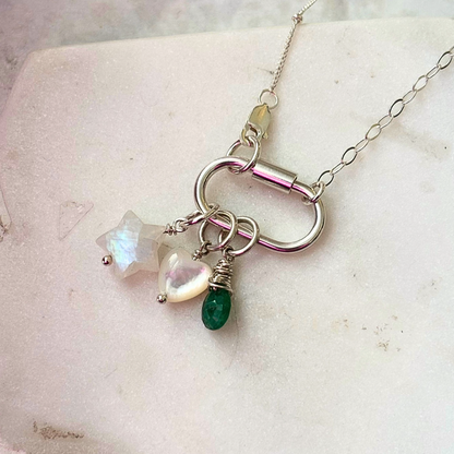 Necklace with star-shaped, heart-shaped, and teardrop-shaped gemstones on a textured surface.