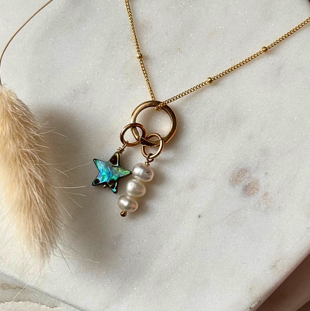 Necklace with star and pearl charm on a marble surface