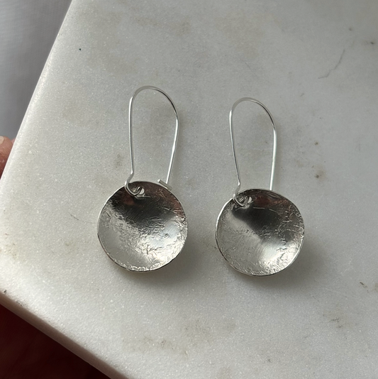 Pair of silver earrings on a light gray surface