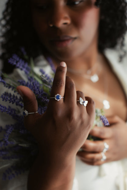 A woman holding flowers and displaying a silver flower ring on her finger.