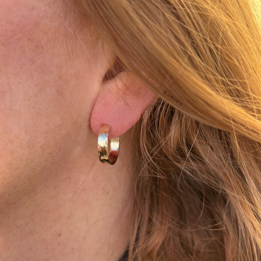 Gold hoop earring worn by a person with blonde hair.