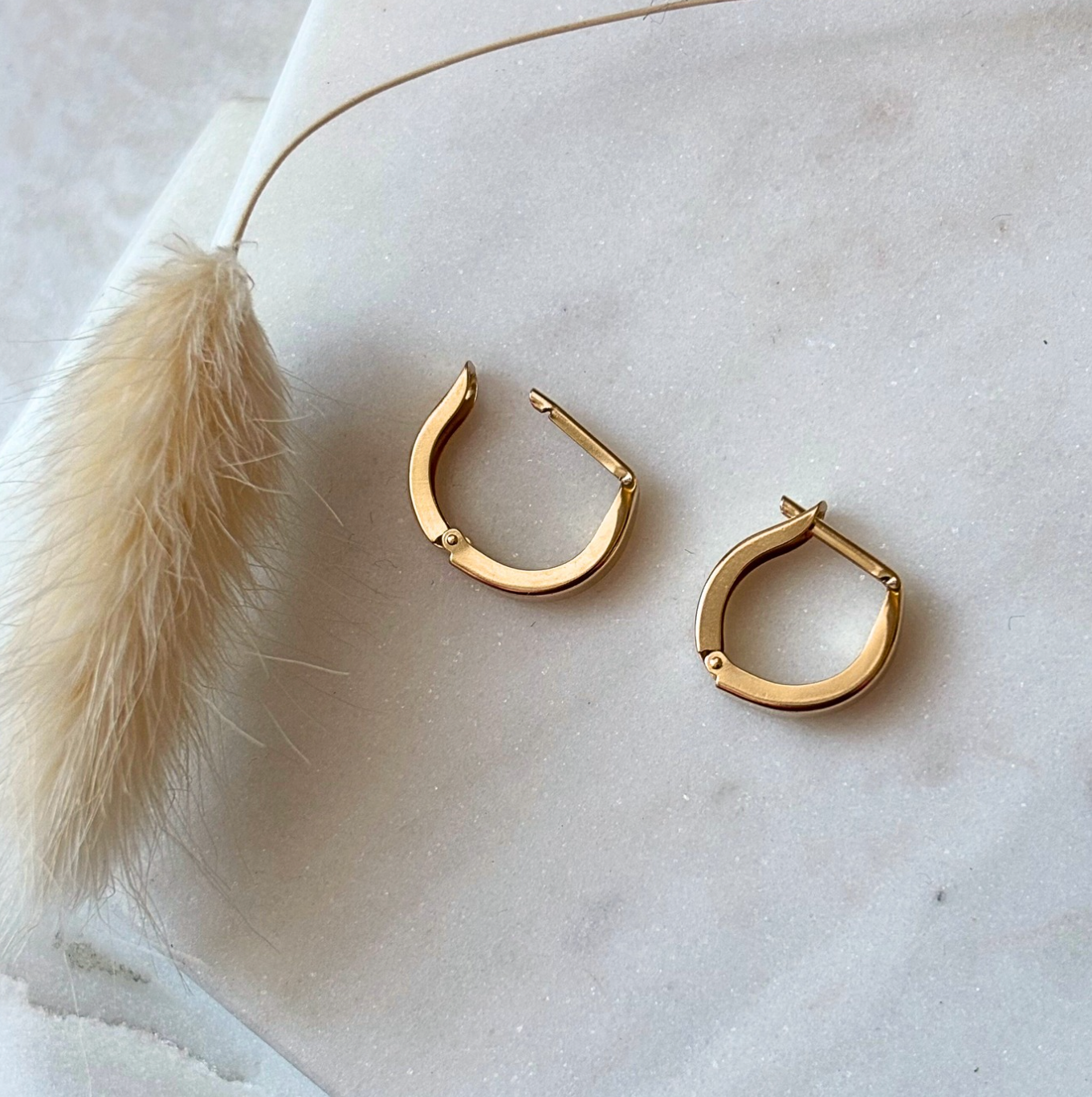 Gold hoop earrings on a light marble surface 