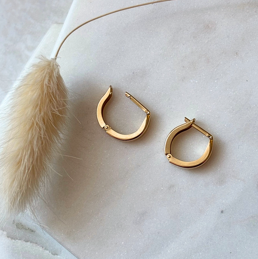 Gold hoop earrings on a light marble surface 
