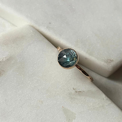A kyanite stacking ring with a blue gemstone, set in a gold-filled or sterling silver band, displayed on a marble surface.