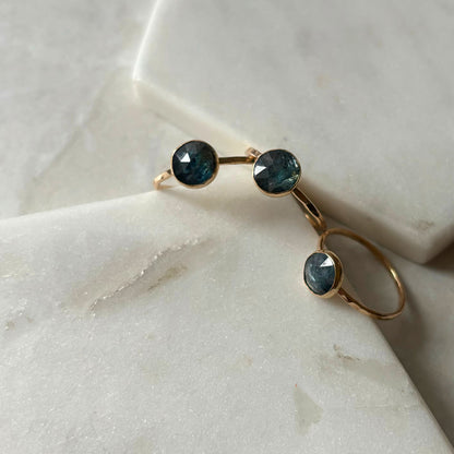 Gold kyanite rings displayed on a marble surface.