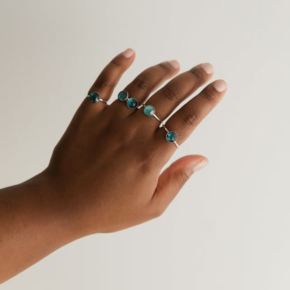 A woman's hand displaying five kyanite rings in silver.