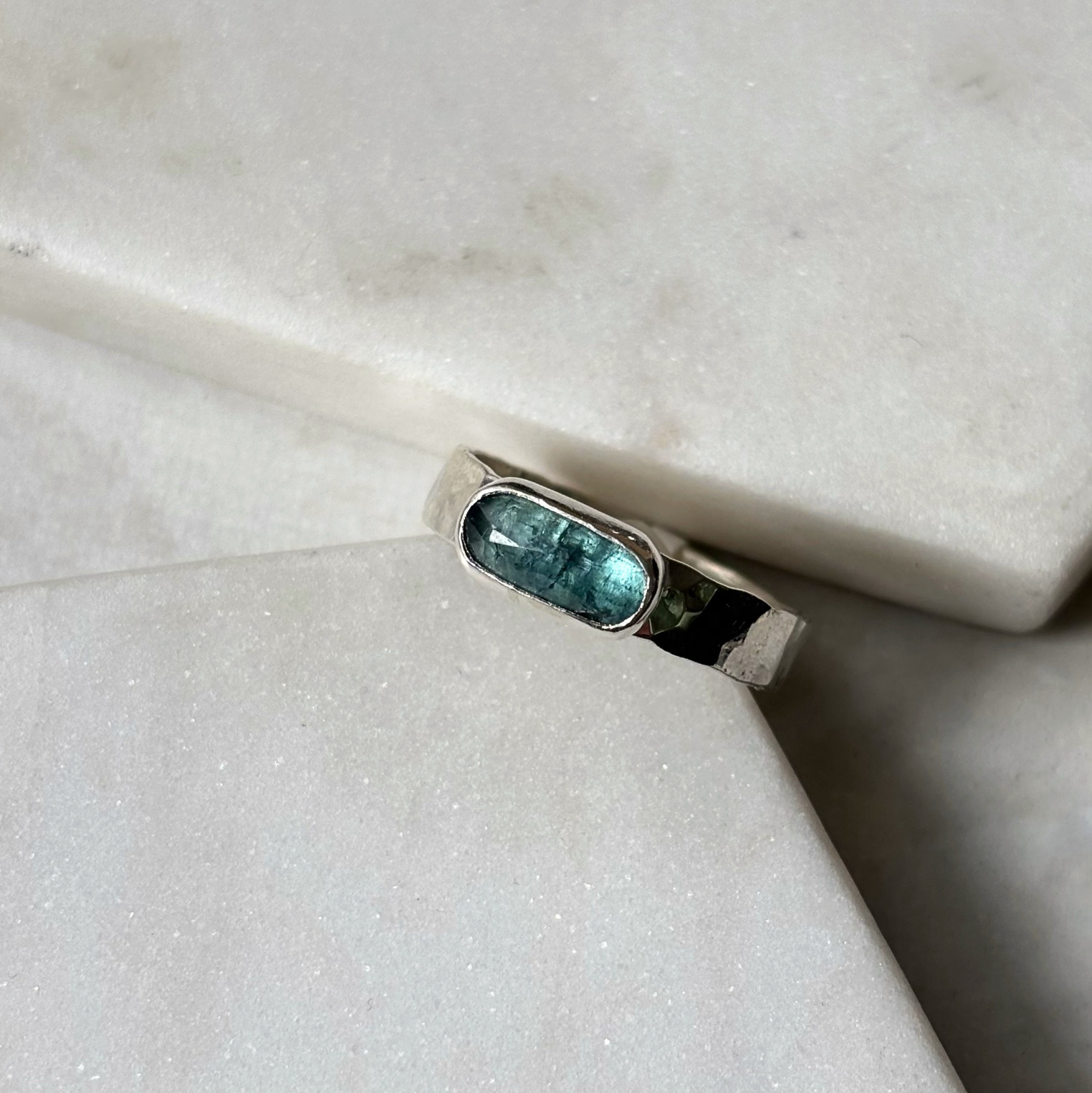 silver ring with a blue gemstone on a marble background