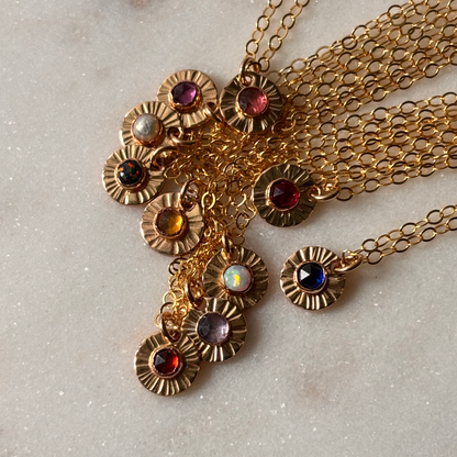 Gold necklace with gemstone pendants on a light gray background