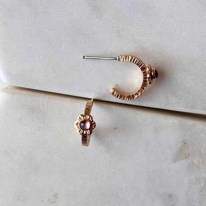 Gold hoop earrings on a textured marble surface