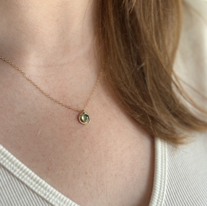 A person wearing a gold moss agate pendant.
