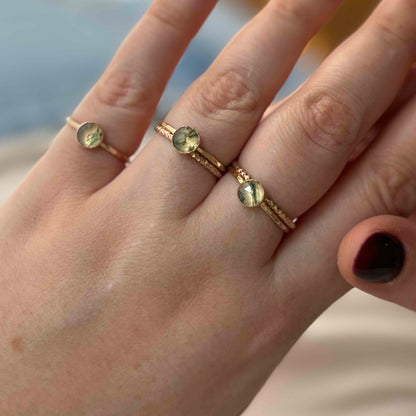 A person wearing three gold moss agate rings.