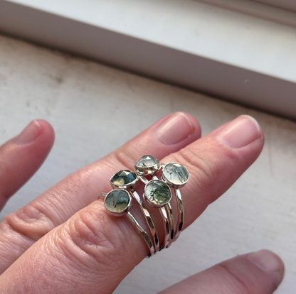 A person wearing silver moss agate rings.