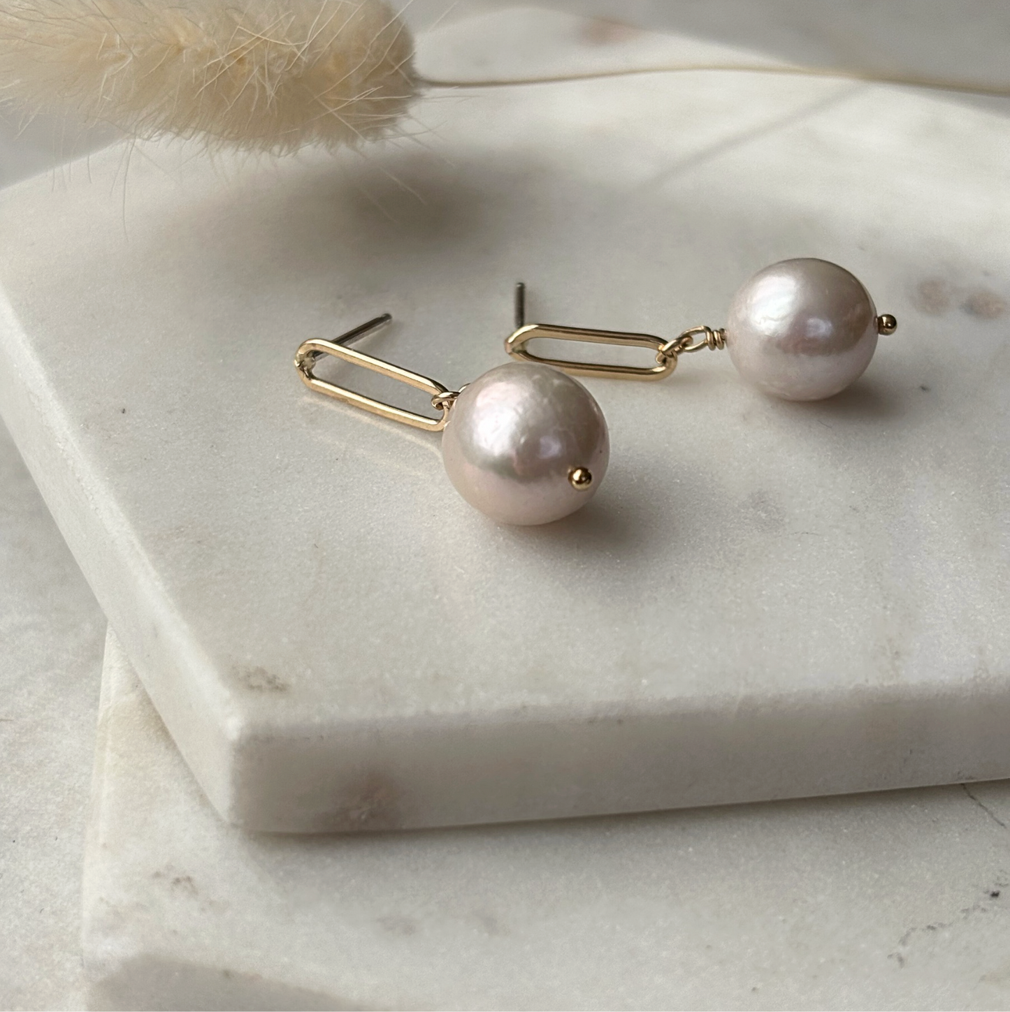 Pearl earrings on a marble surface with a soft focus background