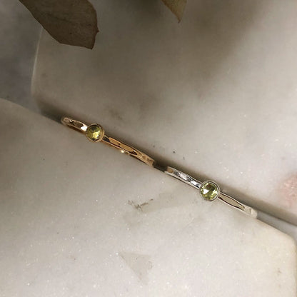 Two gemstone rings in green peridot on a marble background.