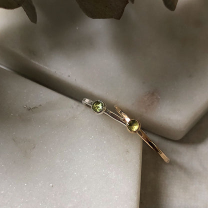 Two peridot gemstone rings in silver and gold.