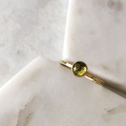 A single Peridot stacking ring with a gold-fill band, placed on a marble surface.