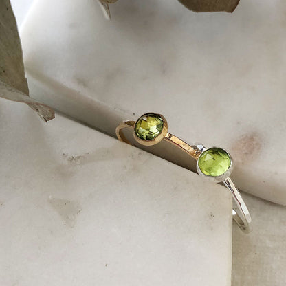 Two peridot gemstone rings in silver and gold fill on a marble background.