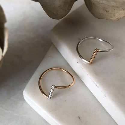 Two rings, with a gold band and silver accents on a marble background.