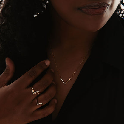 A person wearing a chevron necklace with a combination of silver and gold-fill metals.