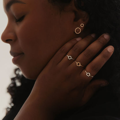 A person wearing small circle gold filled textured orb earrings