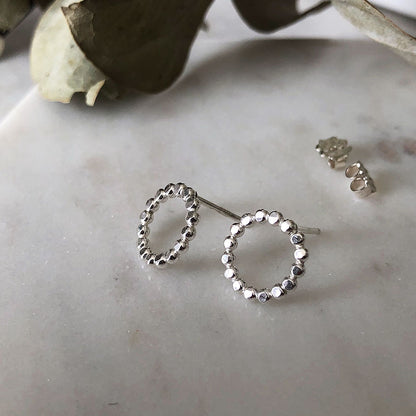 Larger silver circle earrings with a textured surface on a marble background.