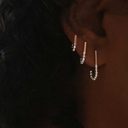A set of three J-hoop earrings made of sterling silver with hand-textured orbs, worn in an ear.