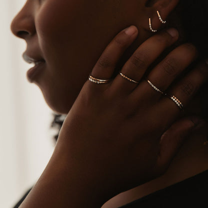 A person wearing rings, with a gold band and silver orb accents.
