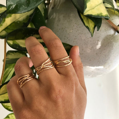 A gold ring with multiple criss crossing wires on a neutral background.