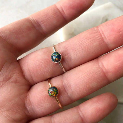 A person wearing sterling silver rings with a black opal stones.