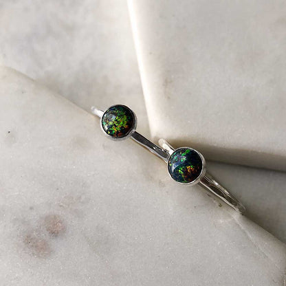 A sterling silver ring with a black opal stone placed on a marble surface.