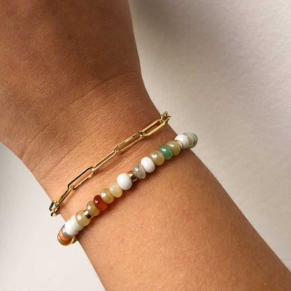 woman's wrist featuring a gold paperclip link bracelet paired with a gemstone bracelet