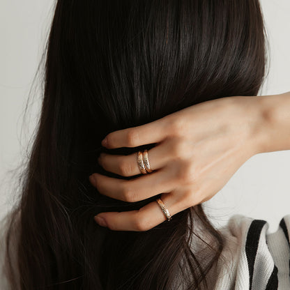 A person wearing three gold floral motif band rings.