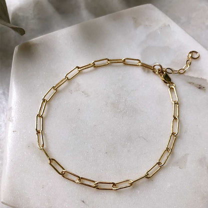 gold paperclip link bracelet on a marble background